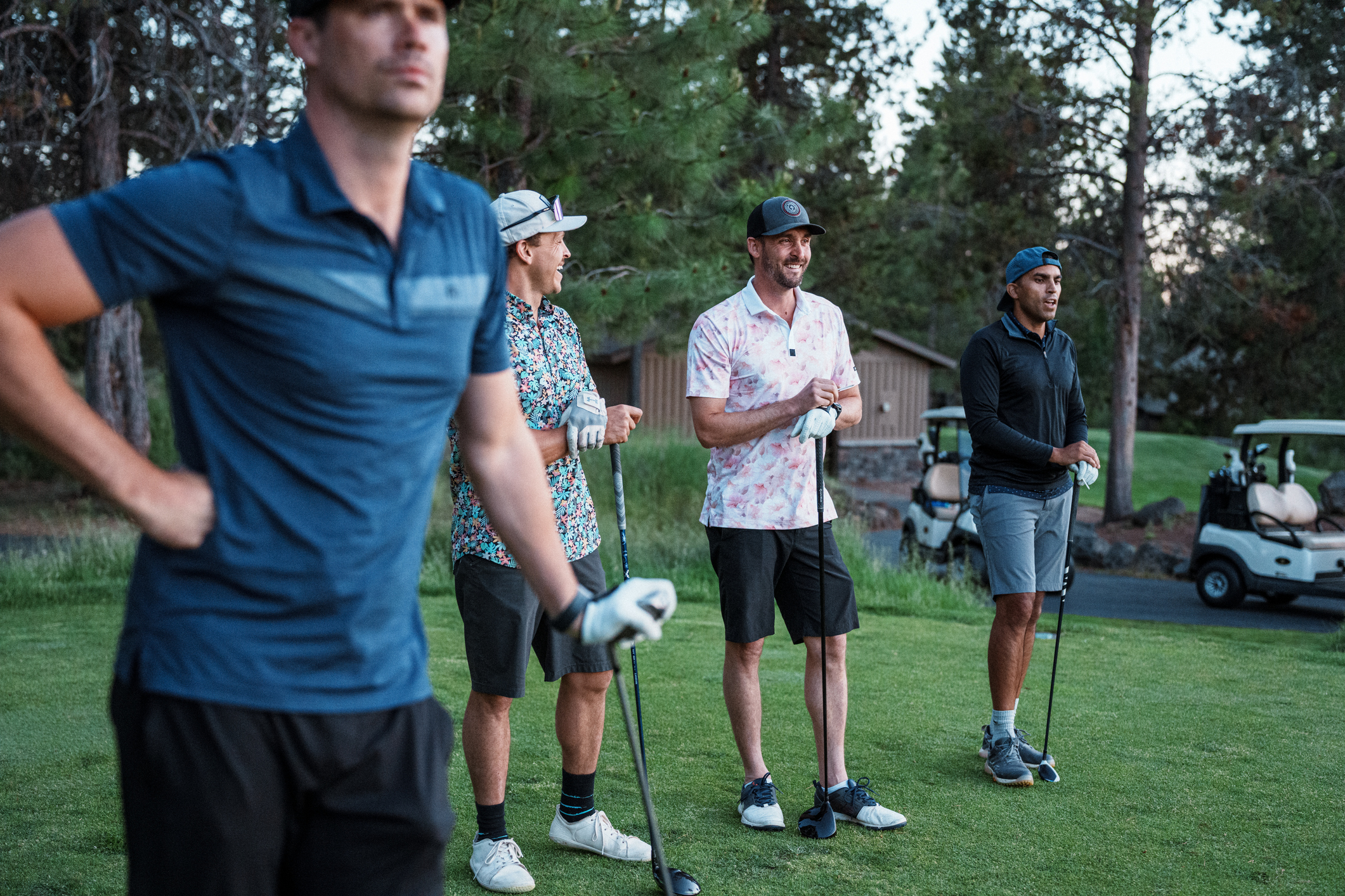 Group of men standing, waiting to tee off on golf course | LMCT