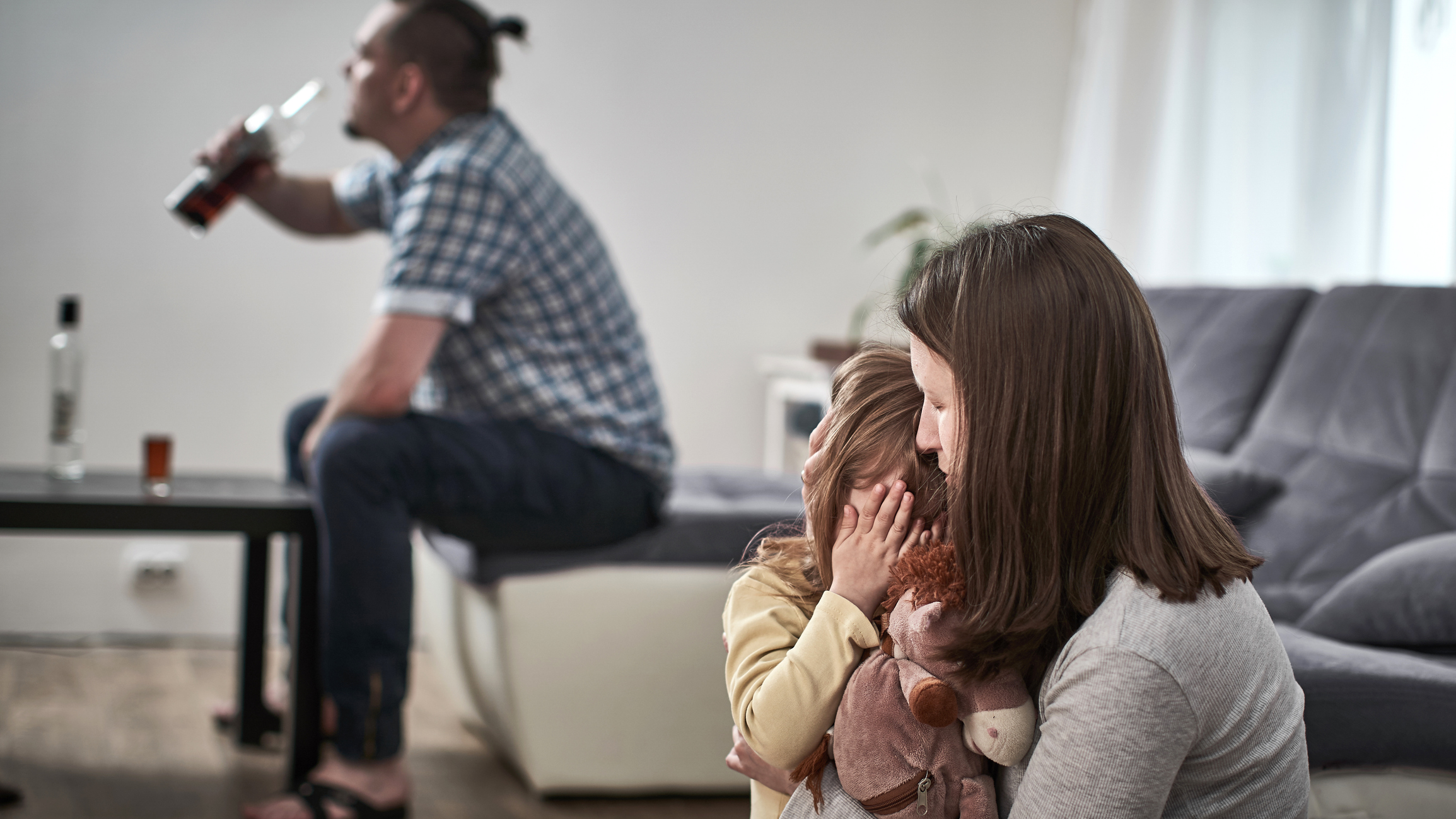 Father drinking on couch | Mother and daughter huddling away from him | LMCT | IMAP